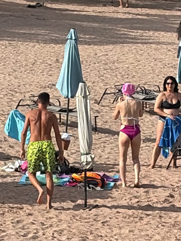 Busy beach day with water activities and mountain backdrop