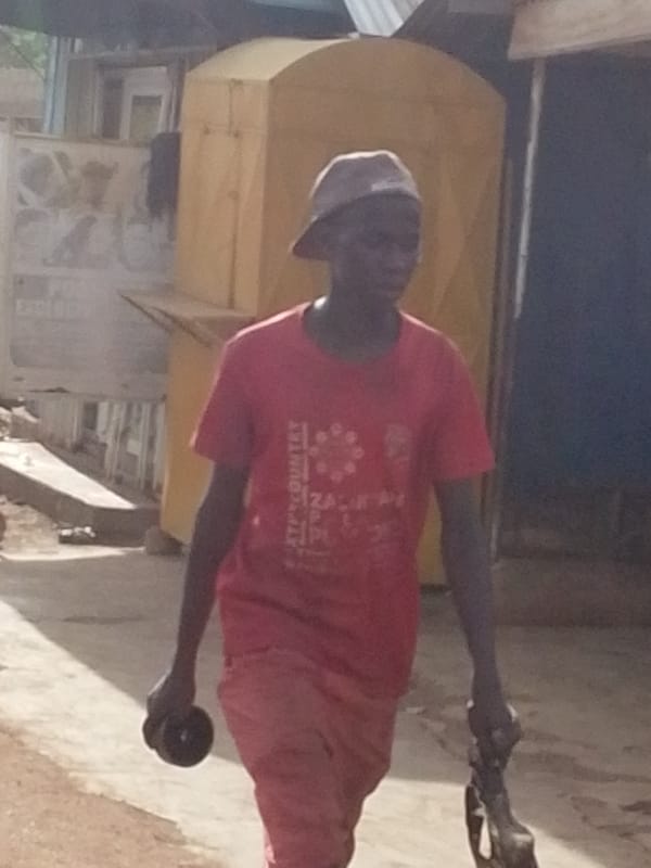 Man walks through Tamale street scene with parked motorcycles