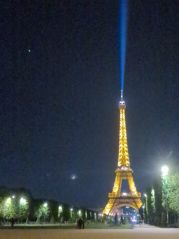 Blue light beam spotted extending from illuminated Eiffel Tower