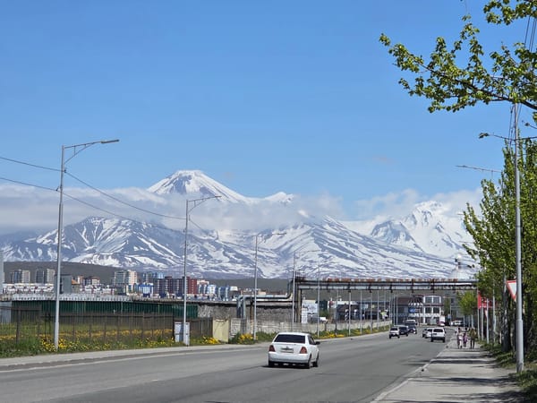 Urban life unfolds beneath snow-capped volcanic mountain backdrop
