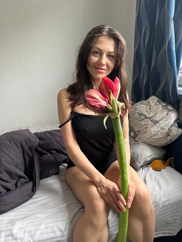 Woman poses with flower in bedroom photography session