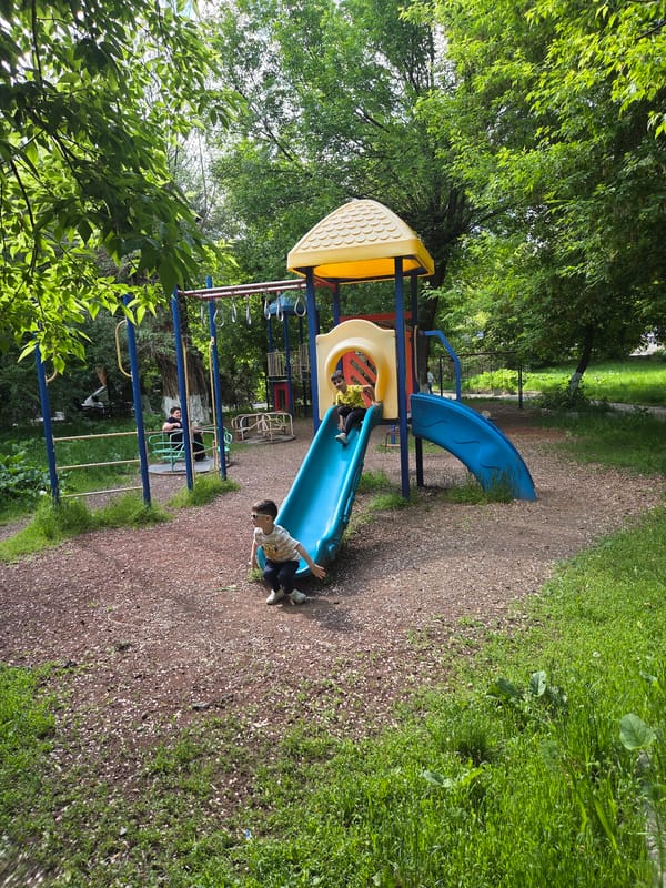 Child plays at playground, fountain, toy cars in Gyumri