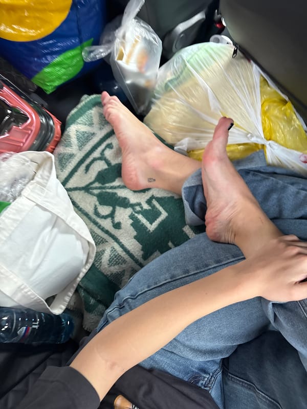 Person sits barefoot in cluttered vehicle cargo area, Sedanovo