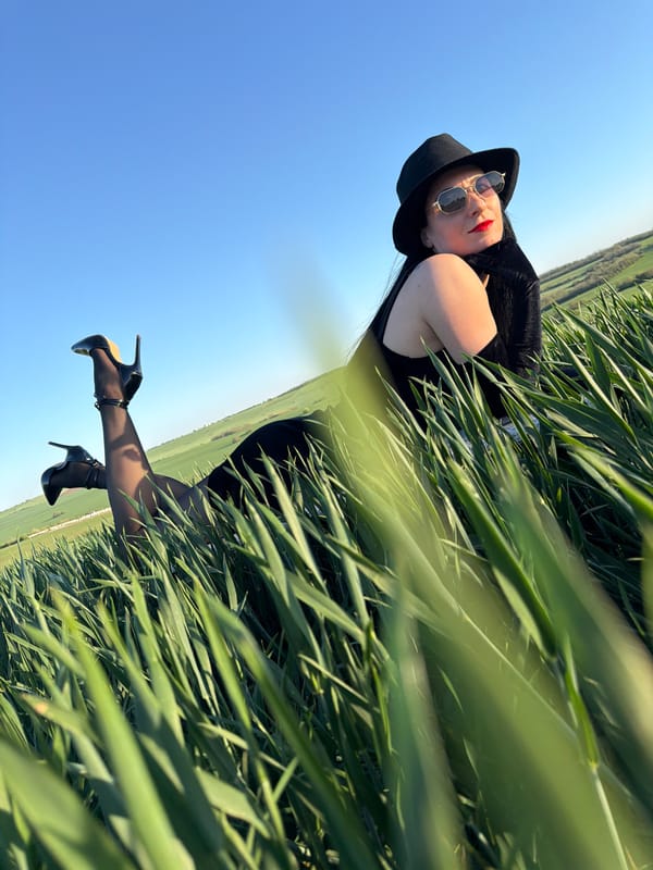 Woman in black dress rests in grassy field near Pleven