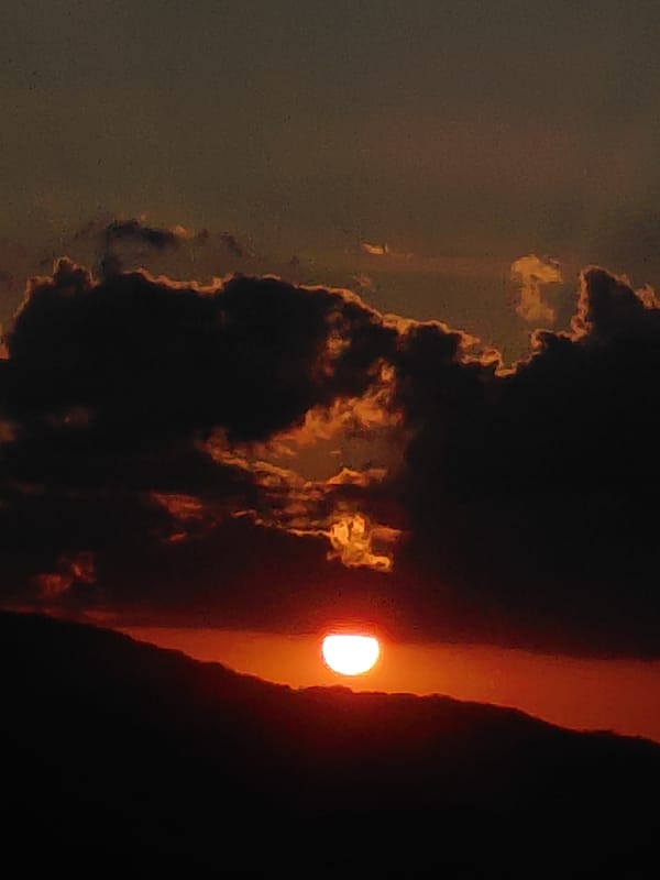 Sunset over Aegio's coastline with a cruise ship in harbor