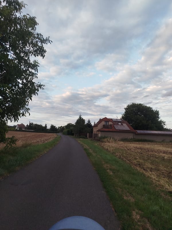 Freshly plowed farmland stretches under a cloudy rural sky
