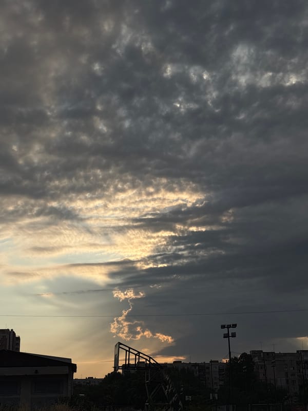 Golden light breaks through cloud cover over an urban skyline.