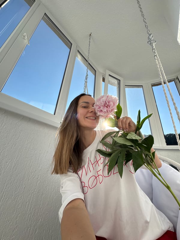Woman documents peony flowers on Sochi balcony during sunny afternoon