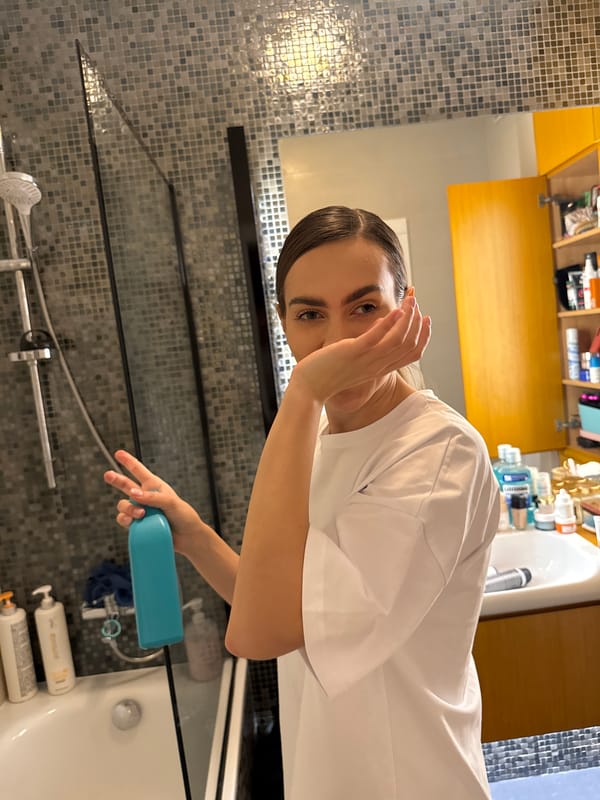 Woman poses with bottle in bathroom mirror selfie