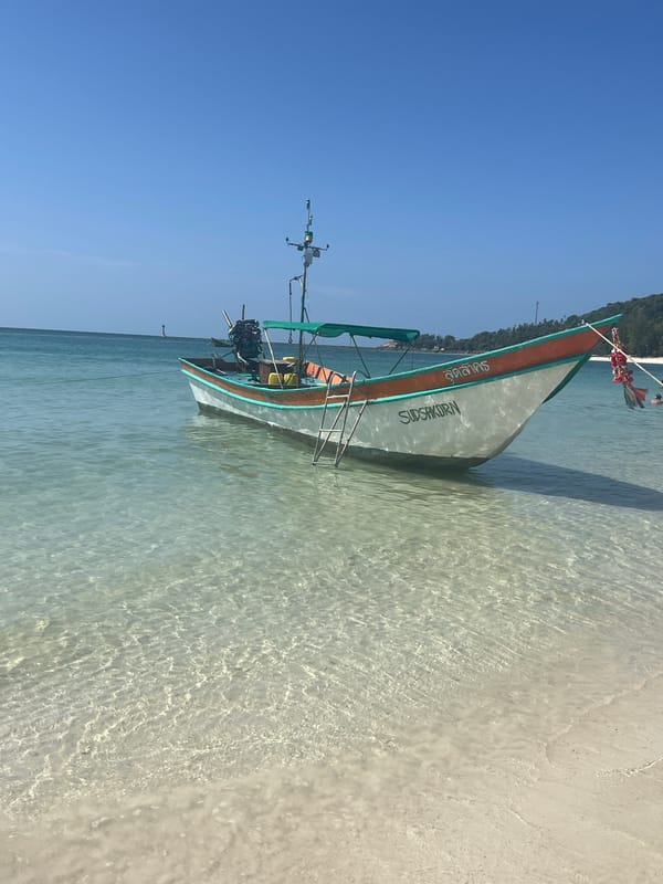 Named boats anchored in clear turquoise shallows near a tropical beach