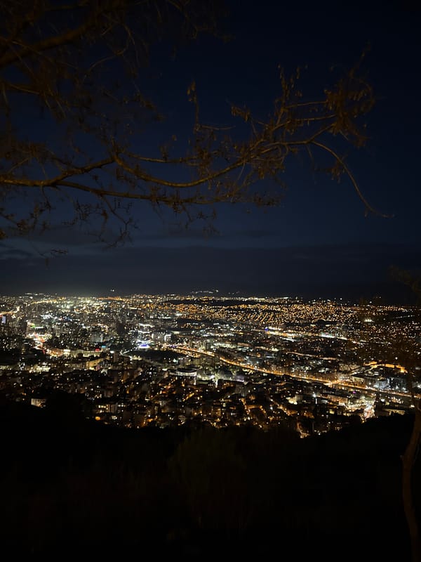 Nighttime aerial view captures illuminated Tbilisi cityscape