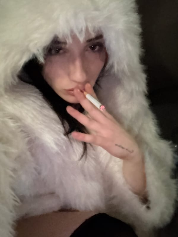 Person in white fur coat smokes on Buenos Aires balcony