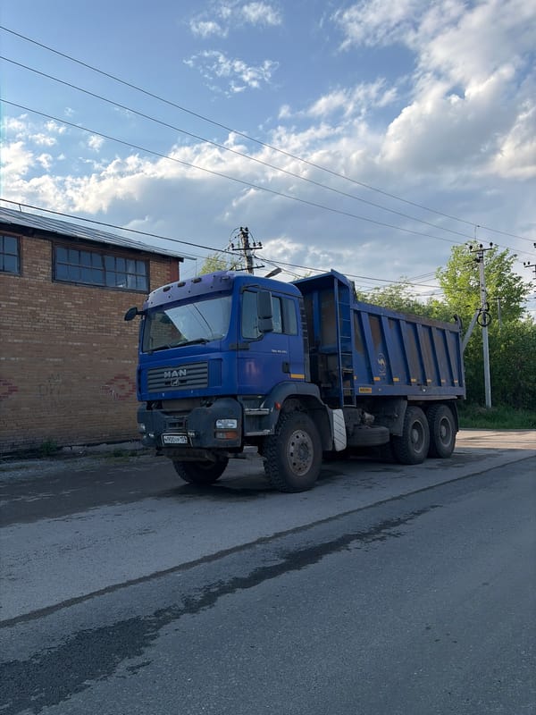 Dump truck parked, traffic flows on Perm residential street