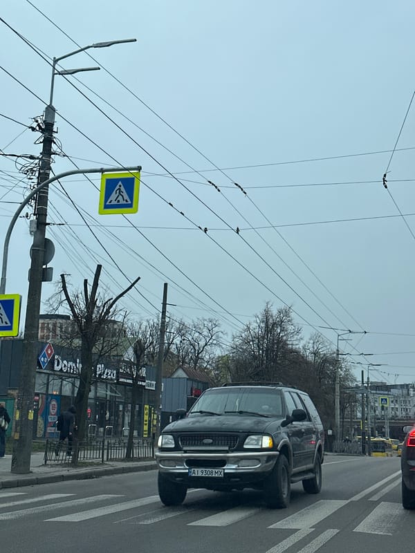 Black Ford SUV crosses zebra crossing in early morning Kyiv