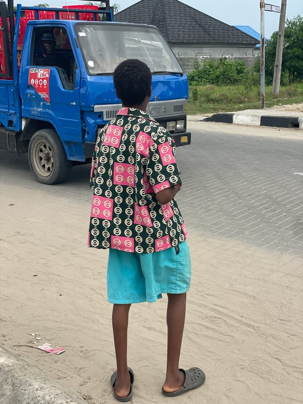 Young man stands by blue Toyota truck in Badagry