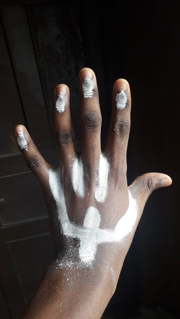 Individual applies white powder markings to hands in Nigeria