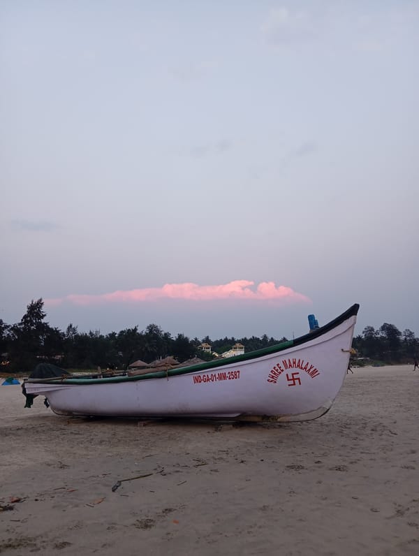 Fishing boat rests on Mandrem beach during sunset