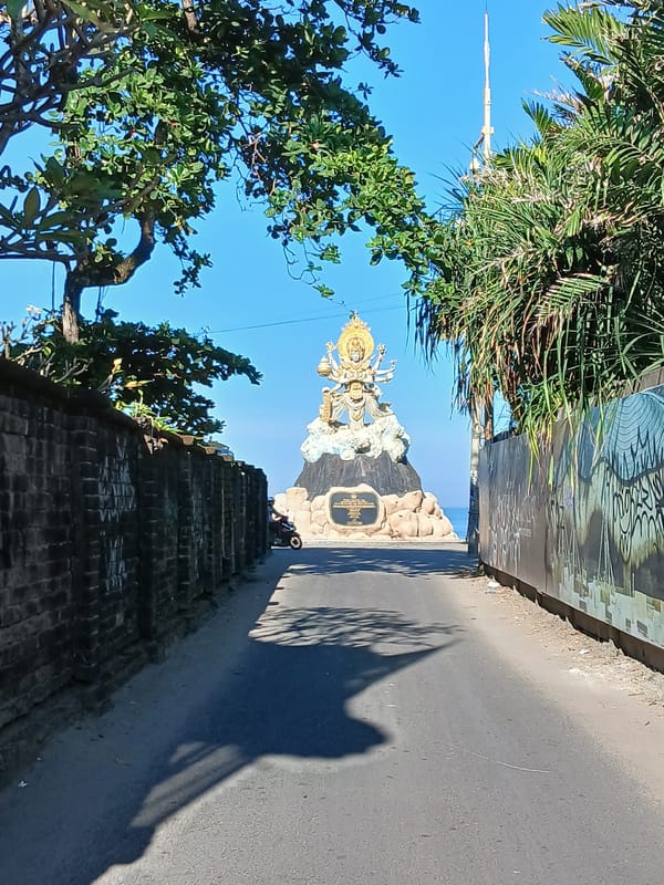 Morning beach life and a coastal deity statue in Bali