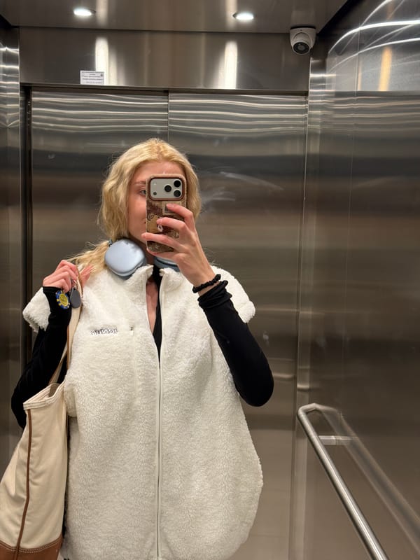 Woman takes elevator selfie in Belgrade wearing white jacket