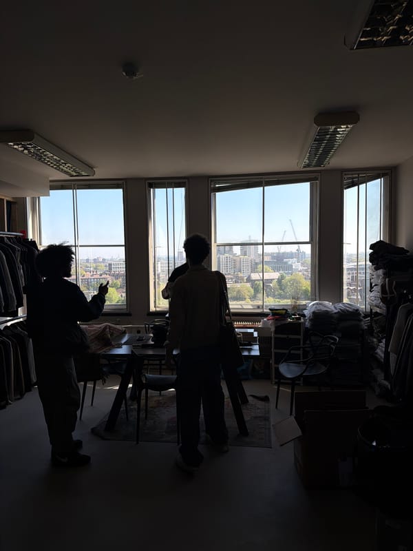 Two people silhouetted against London cityscape windows in daylit room