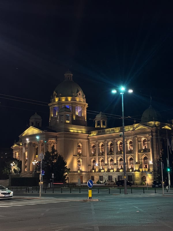 Nighttime pedestrian crossing captured near illuminated Serbian National Assembly