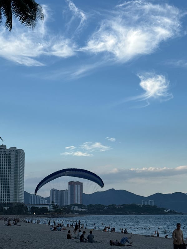 Nha Trang beach buzzing with parasailing, swimmers, and street traffic