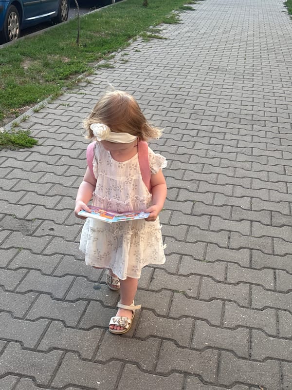 Child in white dress walks Brest sidewalk on a summer afternoon