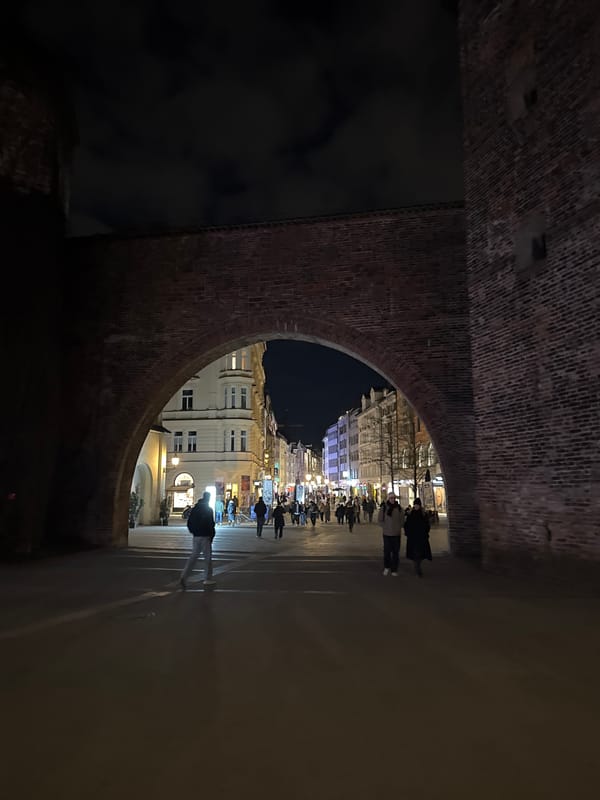 Munich's Karlstor archway frames nighttime pedestrian street scenes