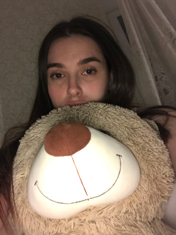 Woman rests with teddy bear in Noviy bedroom