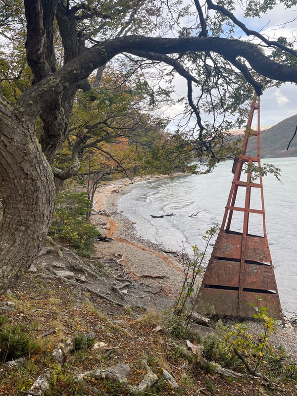Tourists photograph Argentina-Chile border marker and waterfront in Lapataia