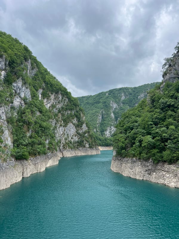 Person observes turquoise gorge waters from Montenegro mountain pathway