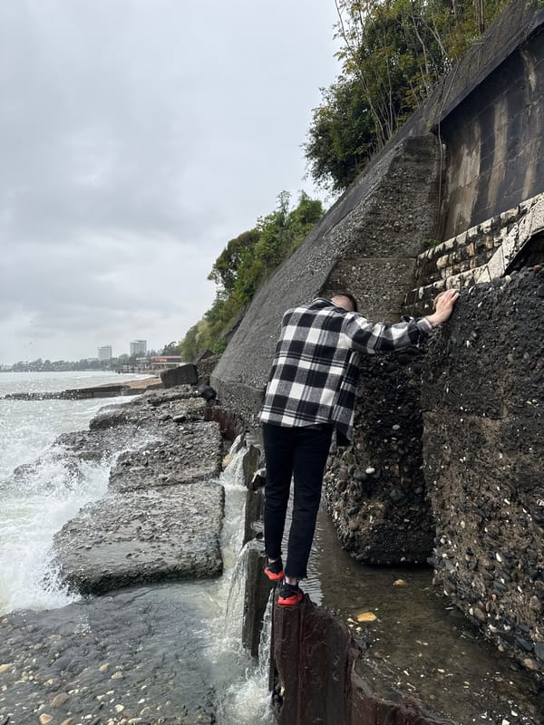 Visitors navigate rocky Black Sea coastline amid crashing waves