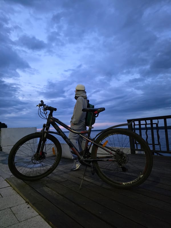 Woman with bike visits Kama River waterfront in Chaikovsky