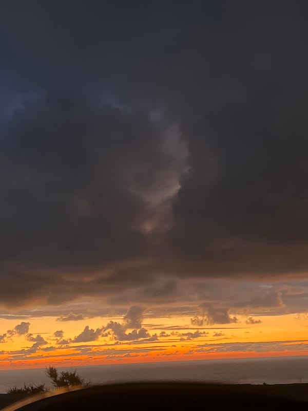 Dramatic storm clouds contrast orange sky over Ahrara, Morocco