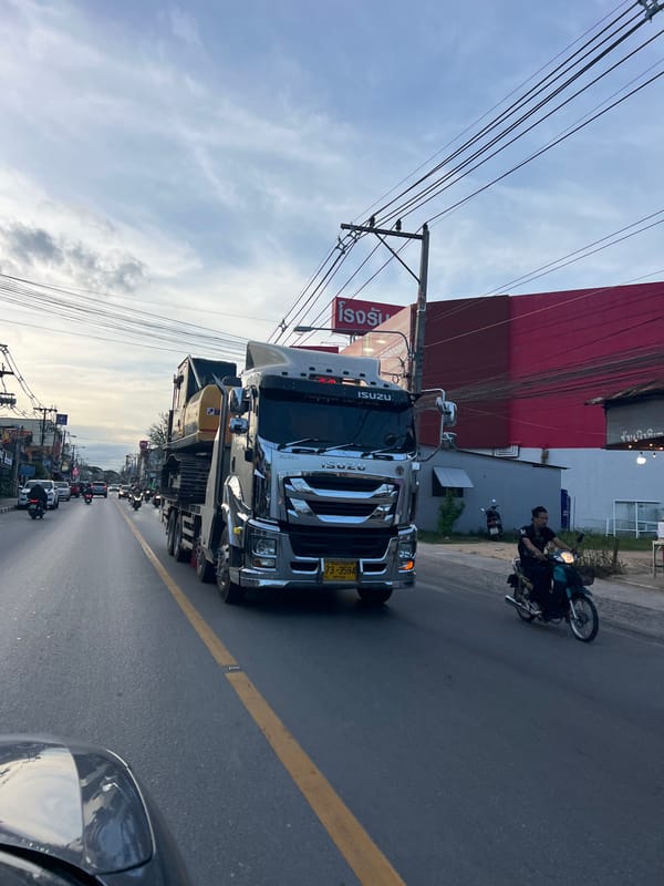 Motorcycle riders navigate street alongside truck in Baan Bo Phut