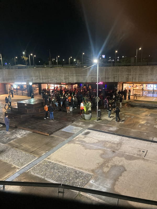 Nighttime crowd gathers in urban plaza, April 2026