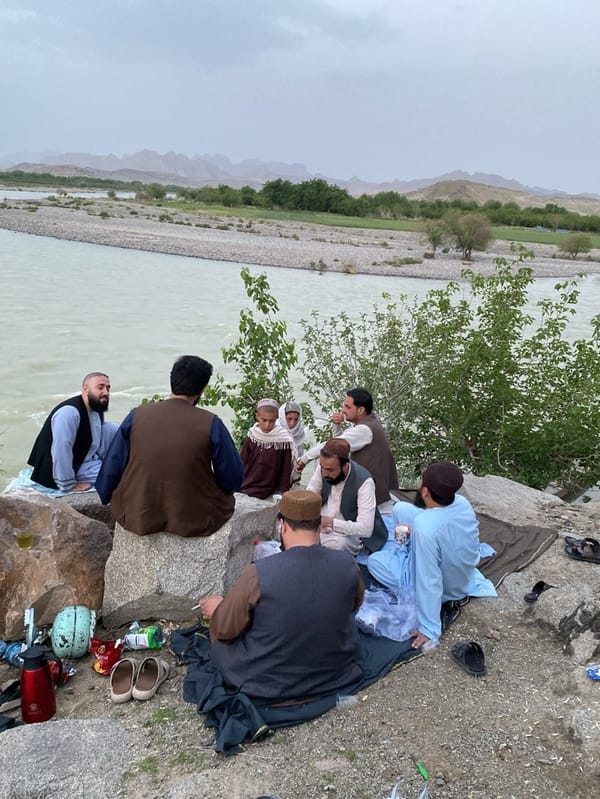 Men gather by muddy river in Afghanistan