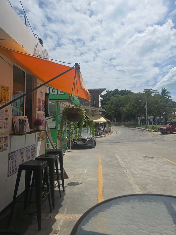 Busy Thai tourist street: scooters, kiosks, and everyday traffic