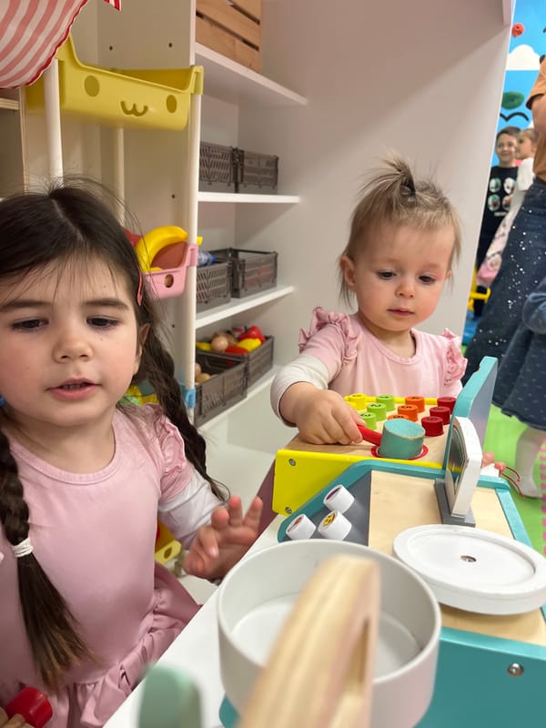 Young girls play with toy cash register in Sofia playroom