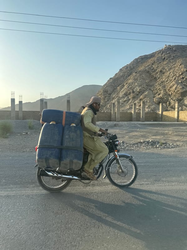 Motorcycle hauling blue liquid containers through Quetta streets