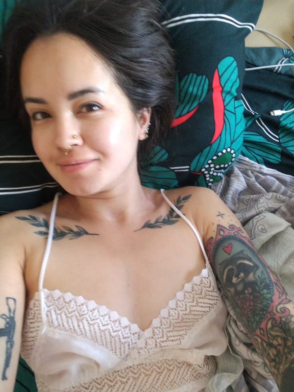 Tattooed woman in white camisole observed resting in Noviy