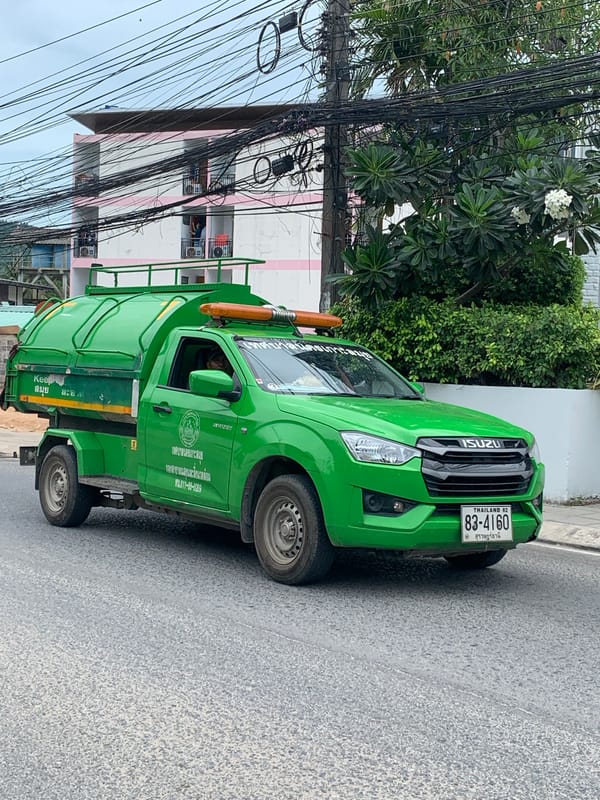 Garbage and Coca-Cola trucks parked on a Ko Samui street