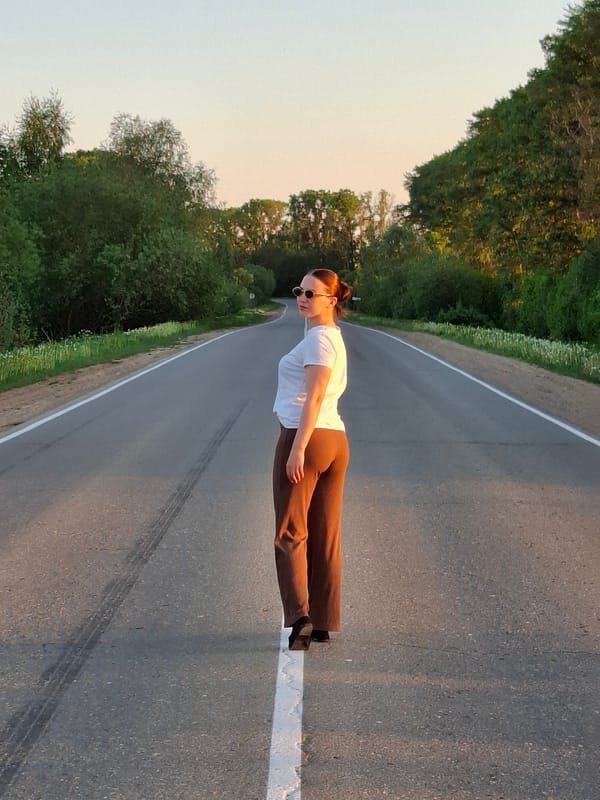 Woman stands on rural road in Rusalevka, Russia