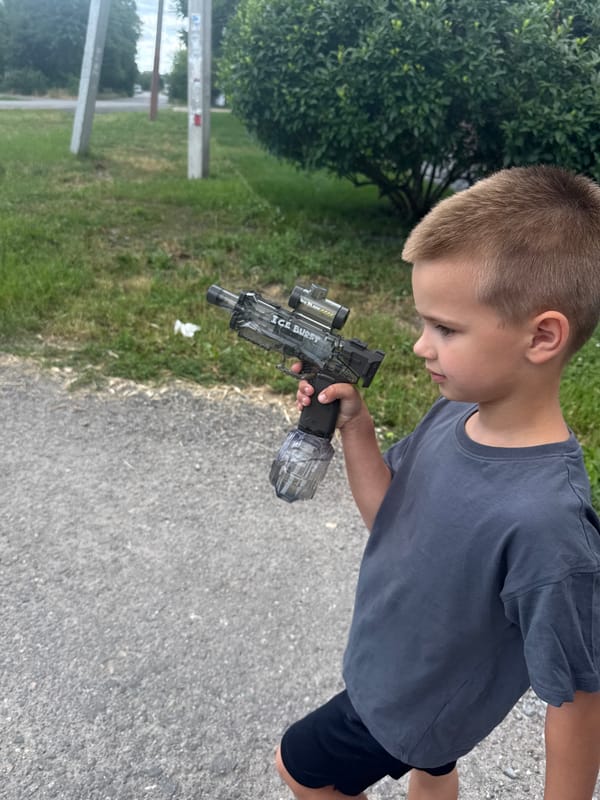 Kid with toy gun roams a quiet Dnipro neighborhood on a summer day