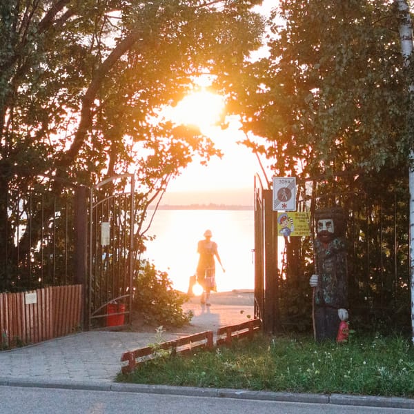 Silhouetted figure walks toward sunset through arched gateway