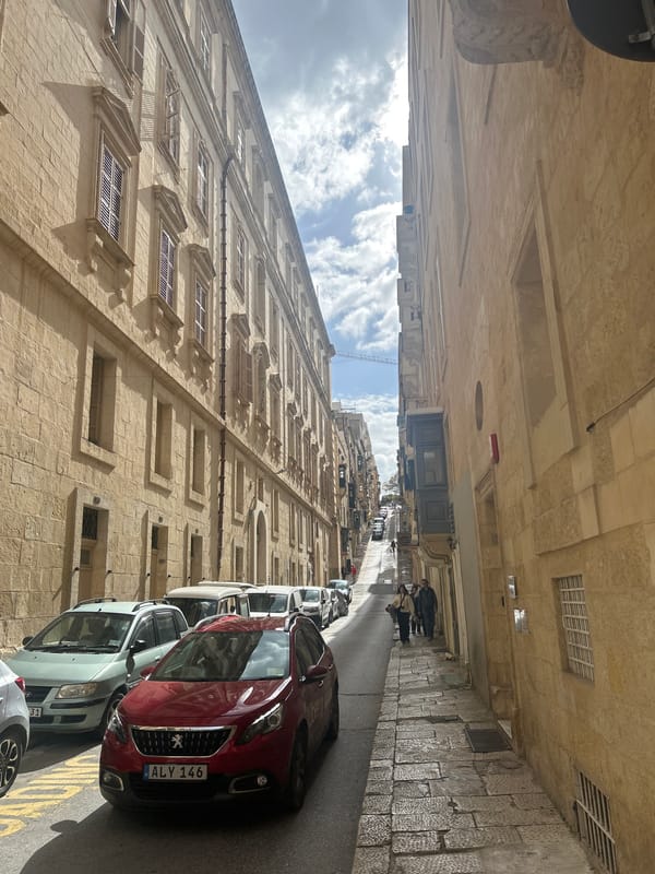 Historic stone buildings line narrow street in Valletta Malta