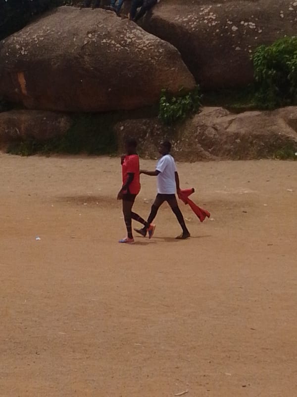 Kids playing soccer and hanging out on a rocky dirt field