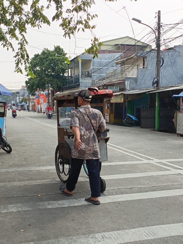 Street food cart crossing a North Jakarta intersection