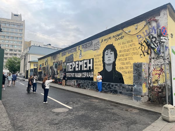 Busy Russian pedestrian street with shops, street art, and a delivery robot