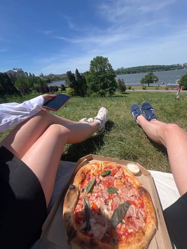 Two people share pizza picnic by lake in Ternopil
